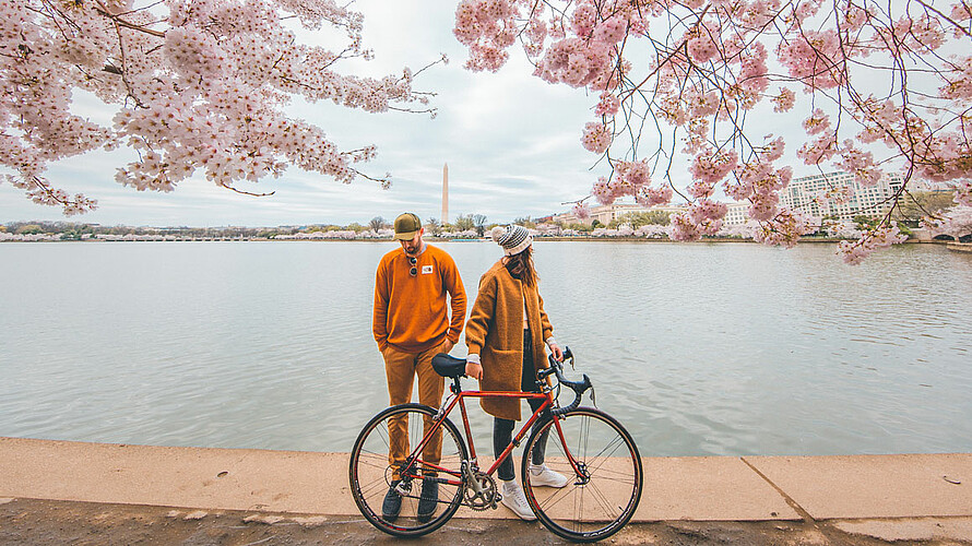 Mann und Frau stehen mit Fahrrad vor einem Fluss.