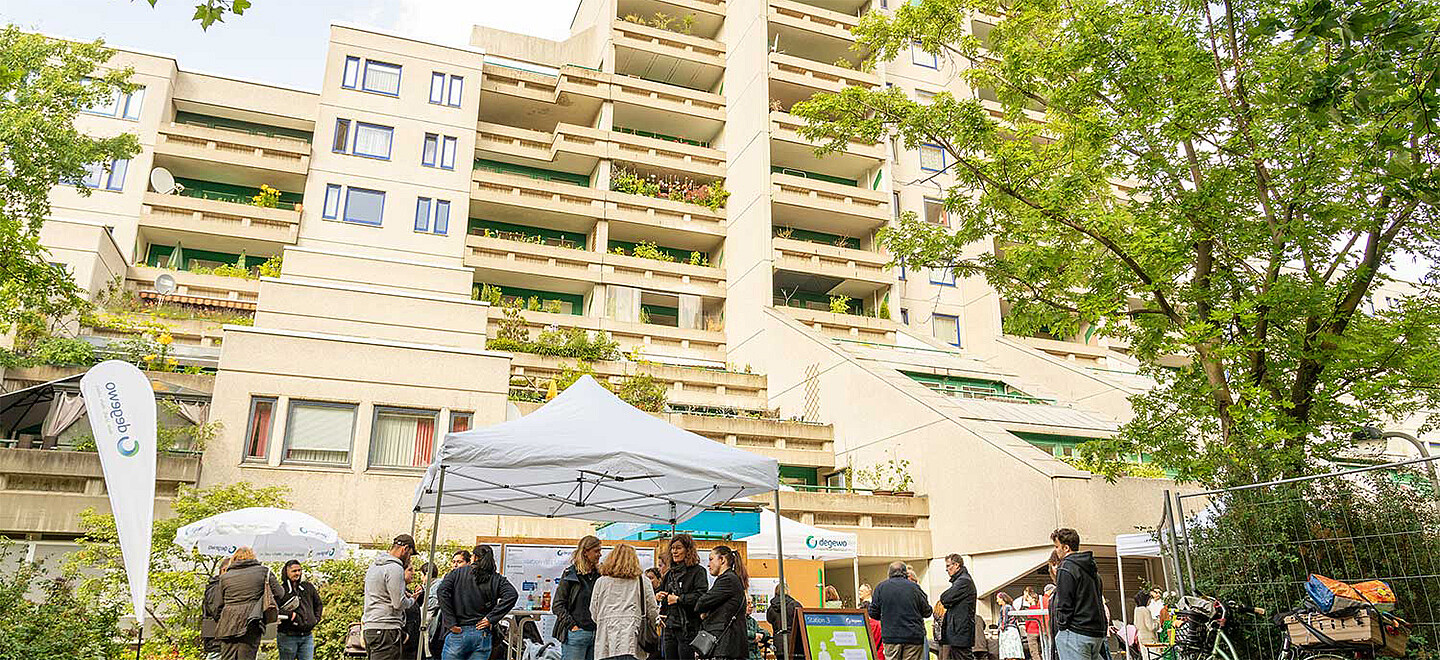 Gruppenaufnahme während der Informationsveranstaltung zur Sanierung der Schöneberger Terrassen. Mitarbeiter von degewo stehen mit Mieterinnen und Mietern vor dem Gebäude zusammen und reden.