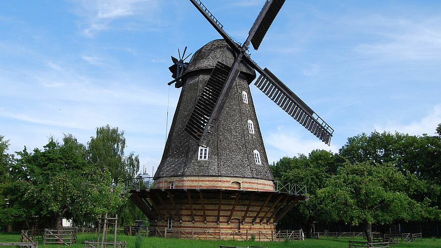 Eine große schwarze Windmühle steht auf einem grünen Rasen.