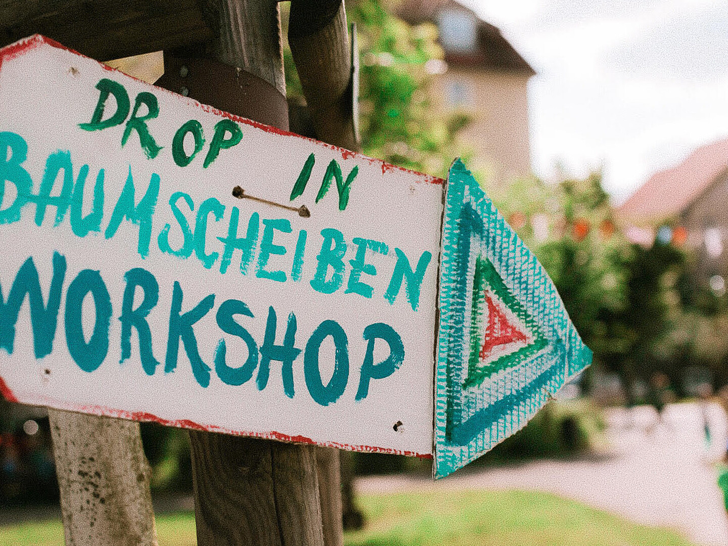 Zu sehen ist ein Pappschild mit der Aufschrift: „Drop In Baumscheiben-Workshop“