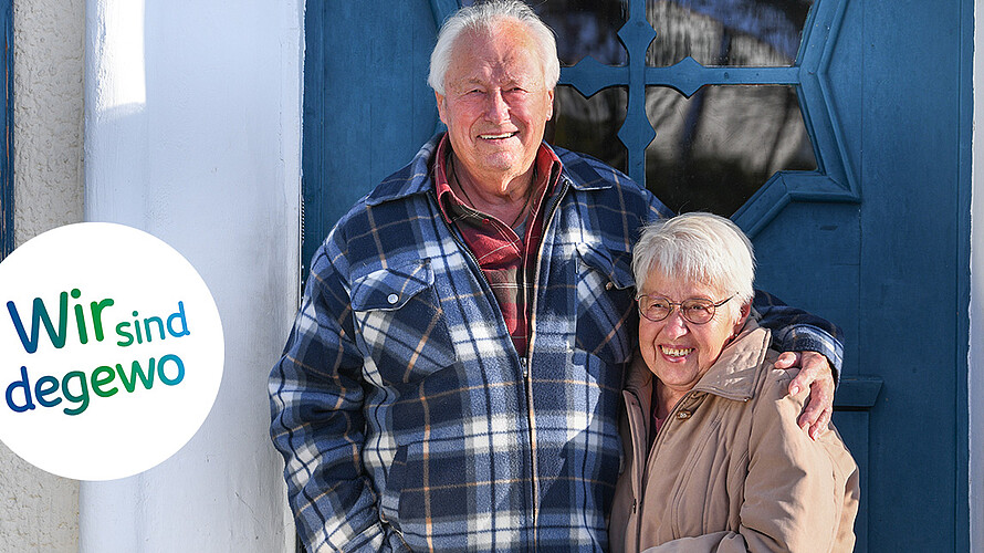 Klaus und Marion Liedtke vor der Eingangstür zu ihrem Haus in der Krugpfuhlsiedlung. Klaus Liedtke hat den Arm um die Schultern seiner Frau gelegt, die beiden lächeln in die Kamera.