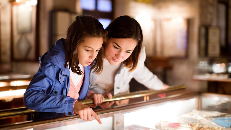 Mutter und Tochter bestaunen Ausstellungsstücke in einem Museum