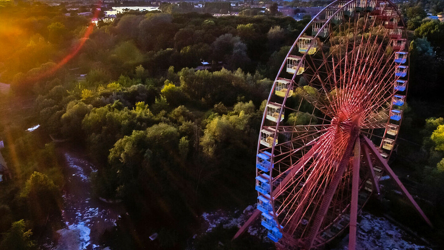 Luftbild von einem Riesenrad mit Wald im Hintergrund.