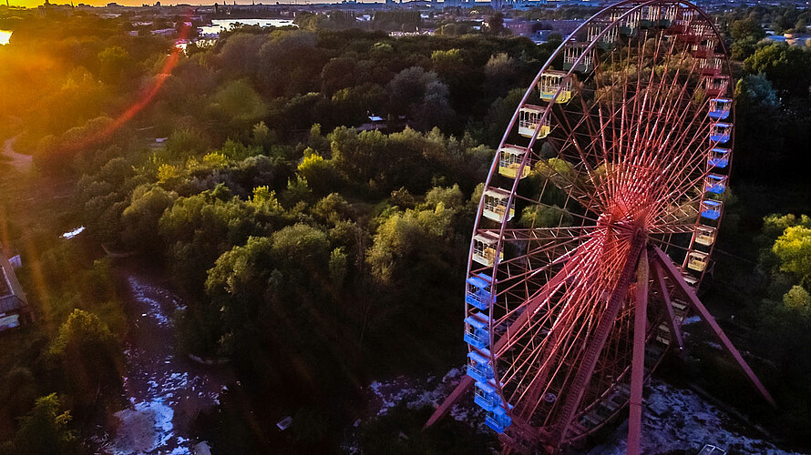 Luftbild von einem Riesenrad mit Wald im Hintergrund.