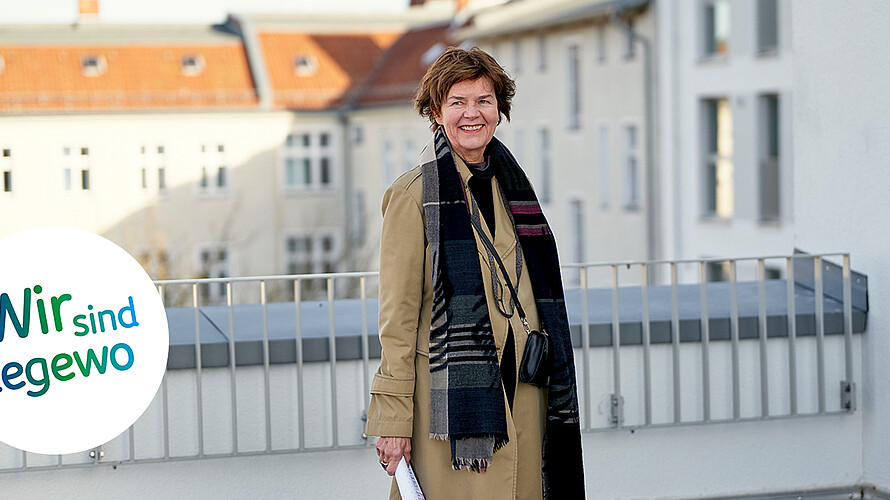 Die Architektin Anne Lampen steht auf einer Dachterrasse eines Neubaus. Im Hintergrund ist eine Kirche zu erkennen. 